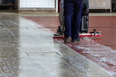 İşçi zemini makineyle temizler.