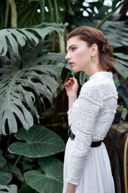 Botanik bahçesinde poz veren güzel bir kız. Makyajlı ve beyaz elbiseli moda tarzı..
