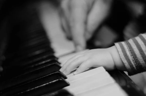 Bliska ręce dziewczynka gry na fortepianie z rąk dorosłych rozmyte w tle — Zdjęcie stockowe