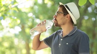 Susuz adamın içme suyu şişe yaz Park. Maden suyu açık egzersiz yaptıktan sonra içme spor adam portresi. Şehir parkında eğitim runner