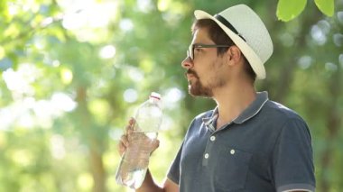 Susuz adamın içme suyu şişe yaz Park. Maden suyu açık egzersiz yaptıktan sonra içme spor adam portresi. Şehir parkında eğitim runner