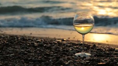 Gün batımında plajda beyaz şarap. Deniz dalgaları