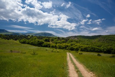 Yaz alan yol ve mavi gökyüzünde bulutlar ile.