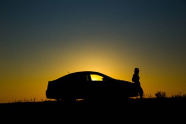 Sedan arabanın silueti ve arka planda güzel bir günbatımı kızı.