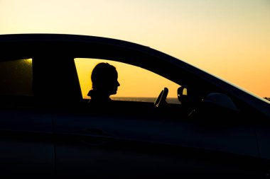 Sedan arabanın silueti ve arka planda güzel bir günbatımı kızı.