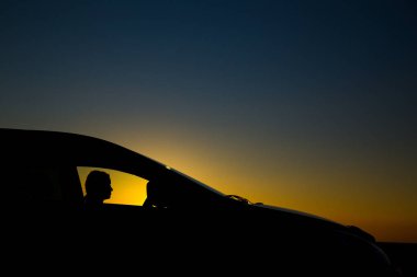 Sedan arabanın silueti ve arka planda güzel bir günbatımı kızı.