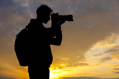 Gün batımında manzara fotoğrafı çeken fotoğrafçı silueti.
