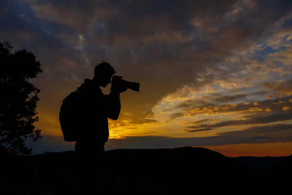 Silueta del fotógrafo tomando fotos del paisaje durante su — Foto de Stock