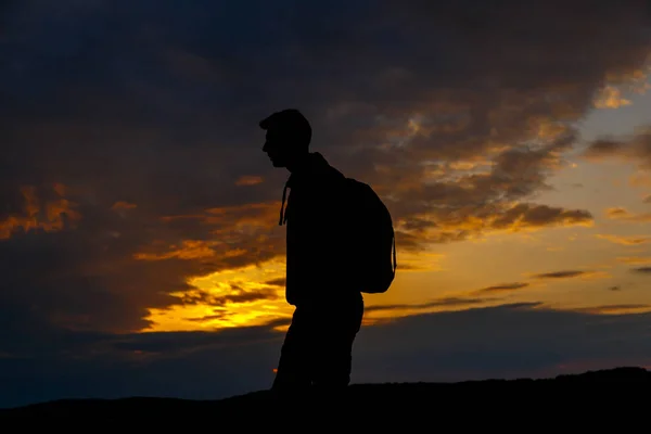 Silhouettes of hiker with backpack enjoying sunset view from top of a mountain. — Foto de Stock