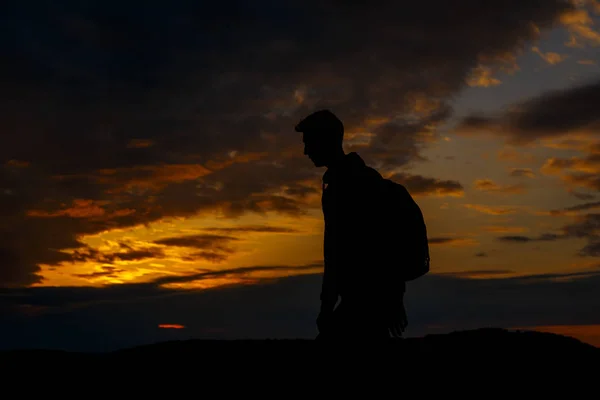 Silhouetten van wandelaar met rugzak genietend van zonsondergang uitzicht vanaf de top van een berg — Stockfoto