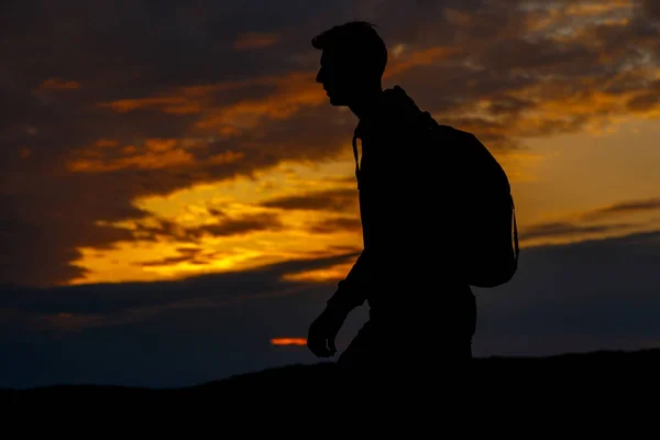 Silhouette di escursionista con zaino che gode di vista sul tramonto dalla cima di una montagna — Foto Stock