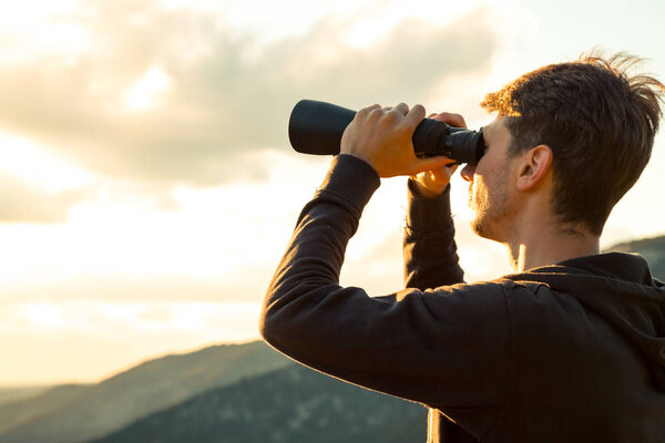 Young Man use of the binocular at forest