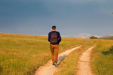Genç adam bir kırsal yolda yürürken