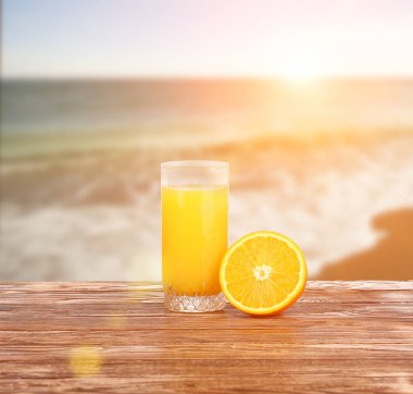 Yüksek cam lezzetli taze portakal suyu ayakta açık ahşap piknik masa üzerinde bir sıcak yaz gününde sıkılmış