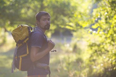 Sırt çantası rahatlatıcı orman ile açık arka plan yaz tatillerini ve yaşam tarzı kavramı ile genç adam Traveler