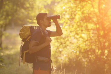 Sırt çantası rahatlatıcı orman ile açık arka plan yaz tatillerini ve yaşam tarzı kavramı ile genç adam Traveler
