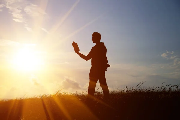 Hombre leyendo en el parque contra el atardecer — Foto de Stock