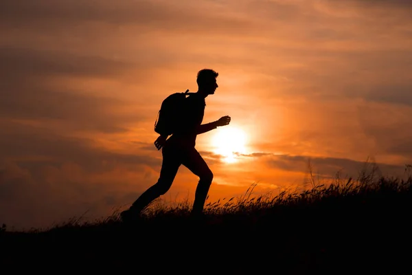 Silhouette di uomo turistico steso mano sulla cima di una montagna godendo il tramonto — Foto Stock