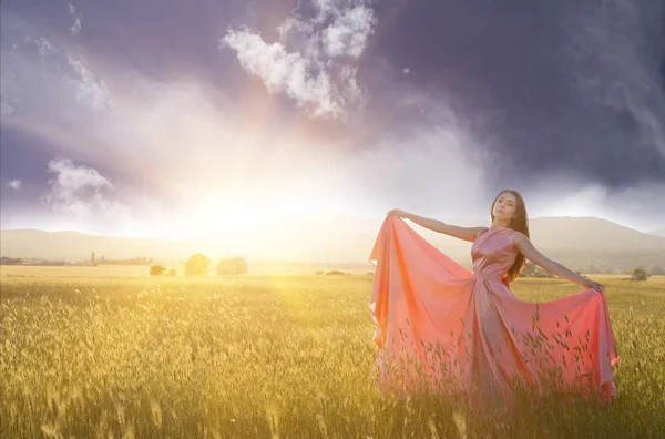 Giovane donna in piedi su un campo di grano con l'alba sullo sfondo — Foto Stock