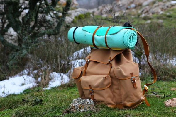 Mochila turística y almohadilla para dormir sobre un fondo de montañas —  Fotos de Stock