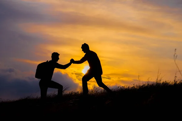 Teamwork Paar Wandern helfen einander, Vertrauen Hilfe Silhouette in den Bergen, Sonnenuntergang. Teamwork zweier Bergsteiger, die sich an der Spitze des Bergsteigerteams gegenseitig helfen, wunderschöne Landschaft bei Sonnenuntergang. — Stockfoto