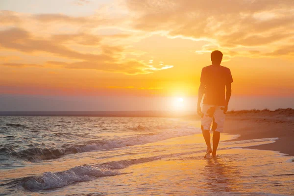 güzel bir gün batımı zemin karşı sahilde yürüyen genç bir adam silüeti