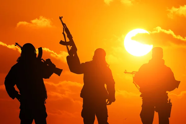three military soldiers silhouetted against a beautiful sunset