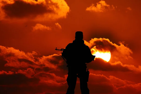 Silhouet van een soldaat met een pistool in de zonsondergang — Stockfoto