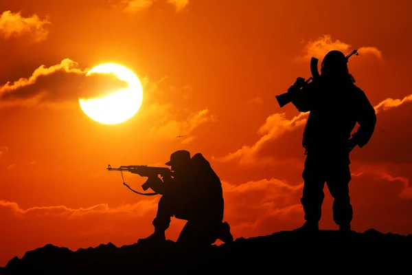 Deux hommes ont abattu un soldat tenant un pistolet et Vit montagne piktureskie bakkdrop al coucher de soleil — Photo