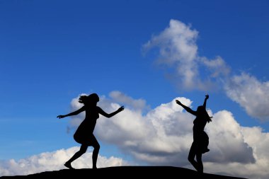 iki kız bir harika gün batımı ve deniz zemin karşı siluet dans