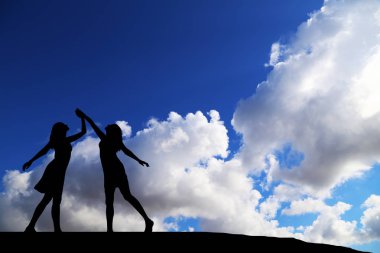 iki kız bir harika gün batımı ve deniz zemin karşı siluet dans