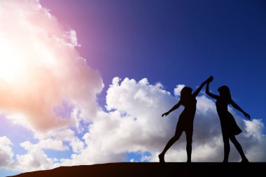 iki kız bir harika gün batımı ve deniz zemin karşı siluet dans