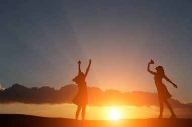 iki kız bir harika gün batımı ve deniz zemin karşı siluet dans