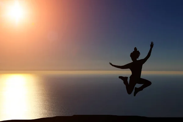 Bela silhueta de uma menina pulando ao pôr do sol — Fotografia de Stock