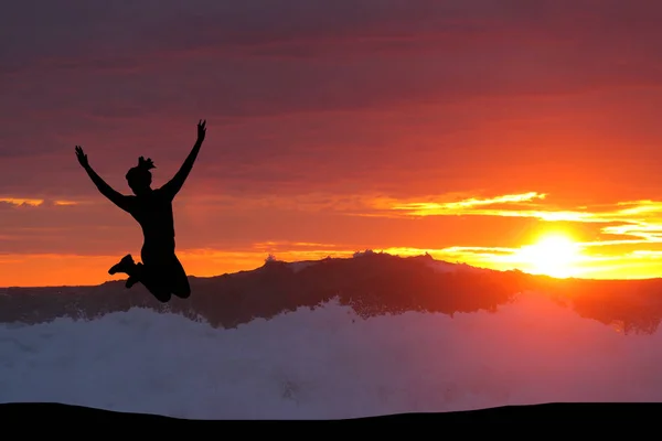 Belle silhouette d'une fille sautant au coucher du soleil — Photo