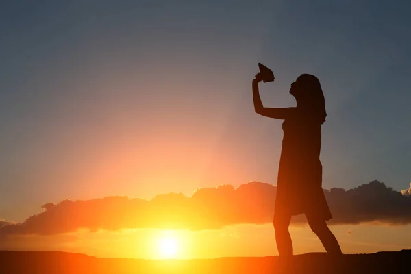Sylwetka dziewczyny o zachodzie słońca niech papierowy samolot — Zdjęcie stockowe