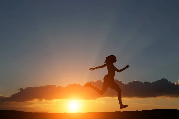 Σιλουέτα του ένα κορίτσι να τρέχει δεξιά λοφίσκο στο όμορφο ηλιοβασίλεμα και στη θάλασσα — Φωτογραφία Αρχείου