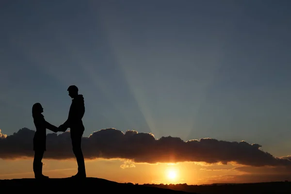 Silhouet jongen en meisje op een mooie zonsondergang hand in hand — Stockfoto