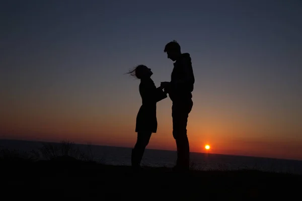 Silhueta cara e menina em um belo pôr do sol de mãos dadas — Fotografia de Stock