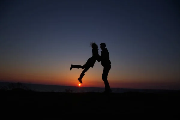 Silhouet jongen en meisje op een mooie zonsondergang hand in hand — Stockfoto