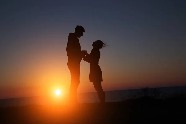 Силуэт парень и девушка на красивом закате держась за руки — стоковое фото