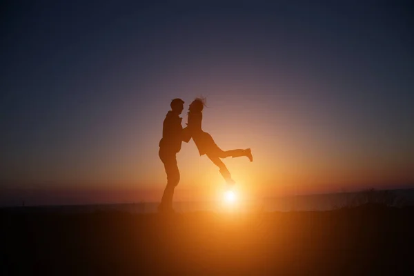 Silhouet jongen en meisje op een mooie zonsondergang hand in hand — Stockfoto