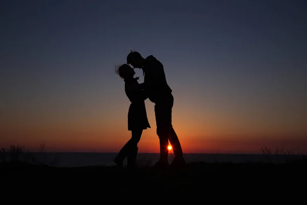Silhouette gars et fille sur un beau coucher de soleil tenant la main — Photo