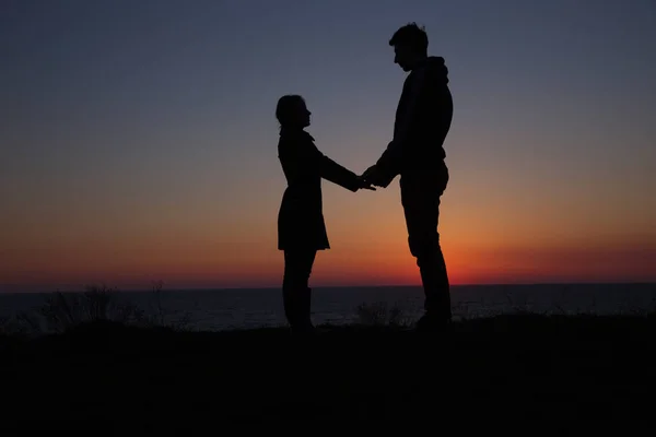 Silhouette gars et fille sur un beau coucher de soleil tenant la main — Photo