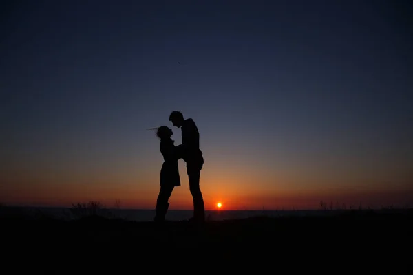 Silhouette ragazzo e ragazza su un bel tramonto tenendosi per mano — Foto Stock