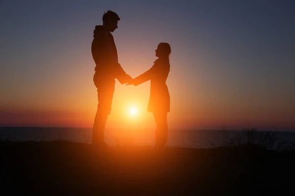 Siluet adam ve kız güzel bir gün batımında el ele tutuşuyorlar. — Stok fotoğraf