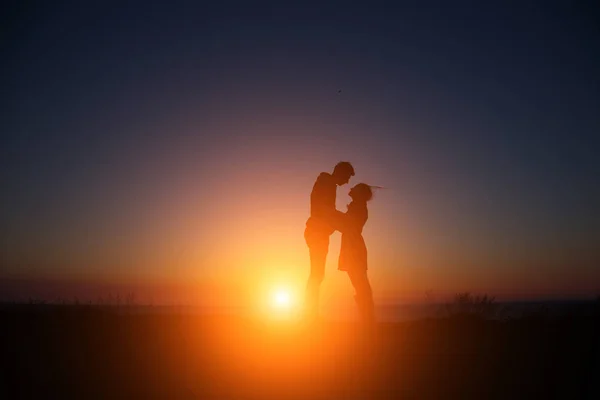 Silhouet jongen en meisje op een mooie zonsondergang hand in hand — Stockfoto