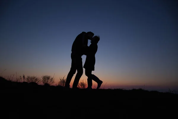 在美丽的夕阳西下手牵手勾勒轮廓的男人和女孩 — 图库照片