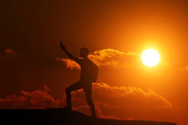 Tepede duran bir adam güzel bir günbatımının arka planındaki bağlantıya bakıyor.