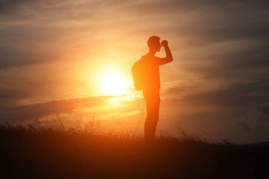 Denize karşı duran bir adam bir dağın tepesinde duruyor ve uzaklığa bakıyor.